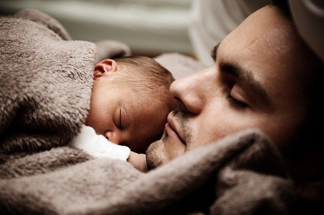 a father sound asleep with baby next to him